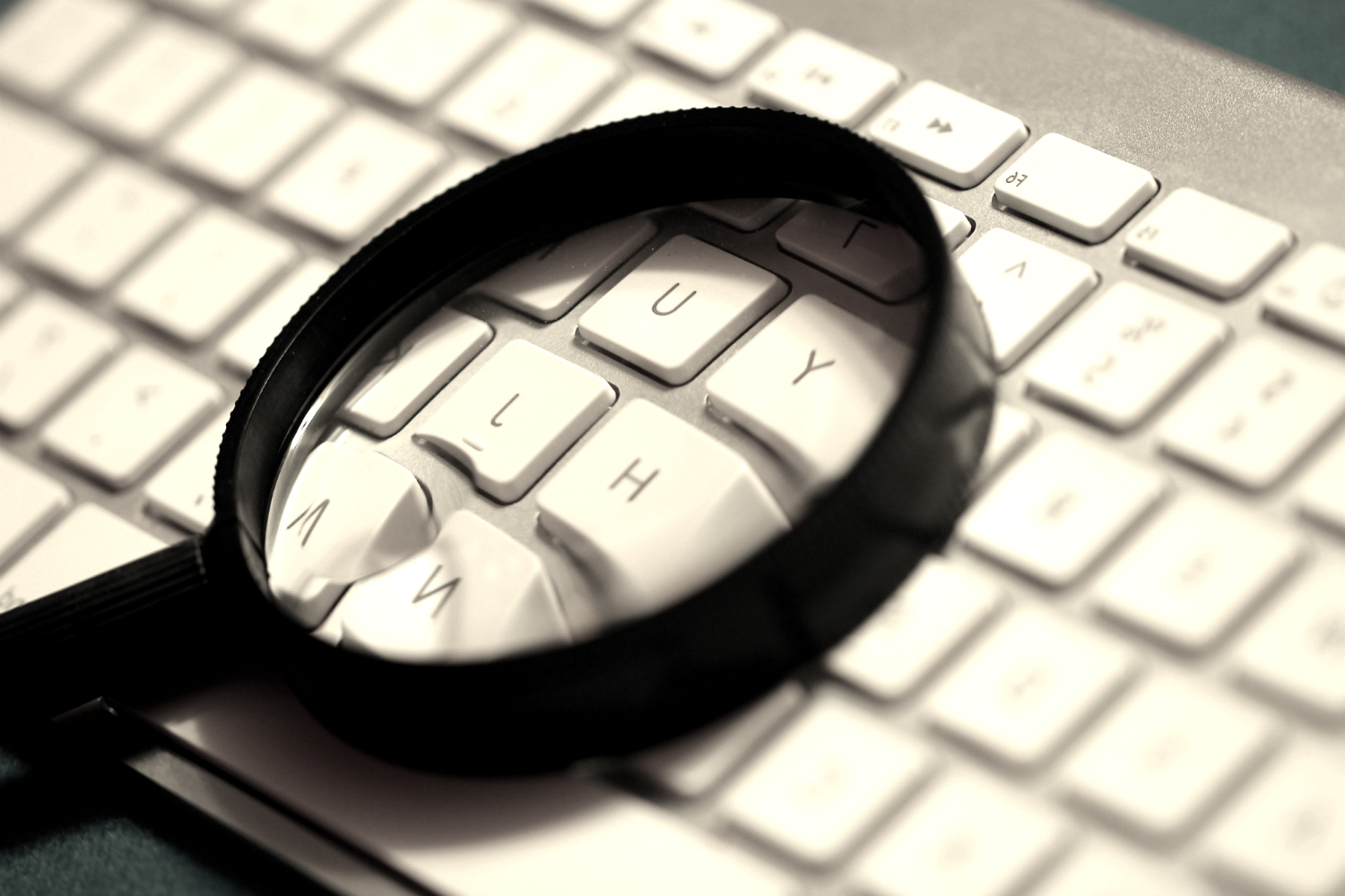 zoomed in on a white keyboard with a black magnifying glass laying on its center